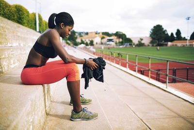 Side view of tired female athlete sitting on steps at stadium