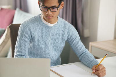 Midsection of man using mobile phone while sitting on table