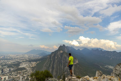 Rear view of man standing on mountain against sky