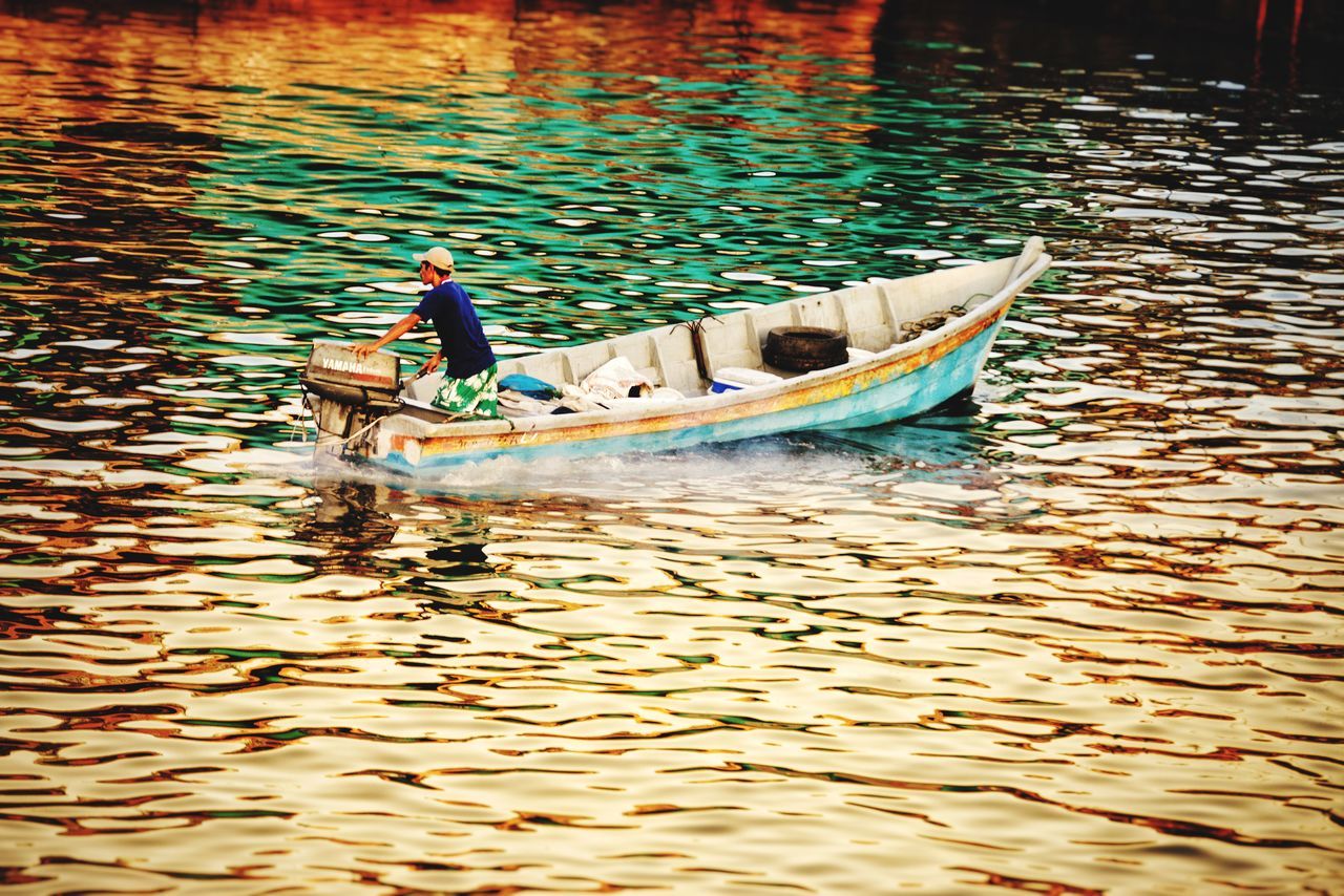 MAN IN BOAT FLOATING ON LAKE