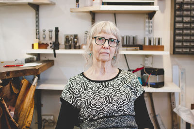 Portrait of confident senior female owner in jewelry workshop