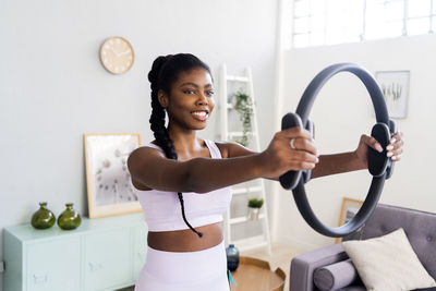 Smiling woman exercising with pilates ring at home