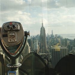 Coin-operated binoculars at observation point by empire state building against sky