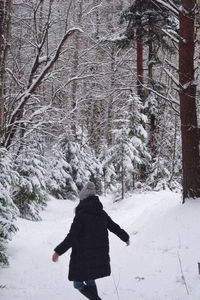 Rear view of person walking on snow covered land