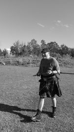 Senior man holding arrow while standing on field during sunny day