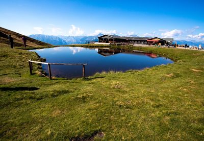 Built structure on field by lake against sky