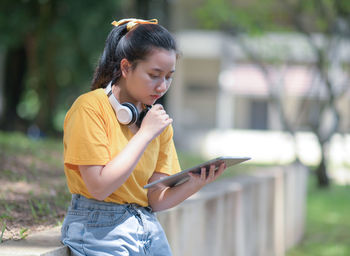 A teenage woman looking down at a tablet in her hand with a worried expression, education concept.