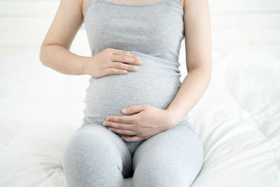 Midsection of woman touching hair on bed