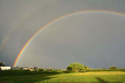 Scenic view of rainbow over field against sky