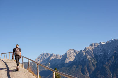 Man standing on railing against mountains