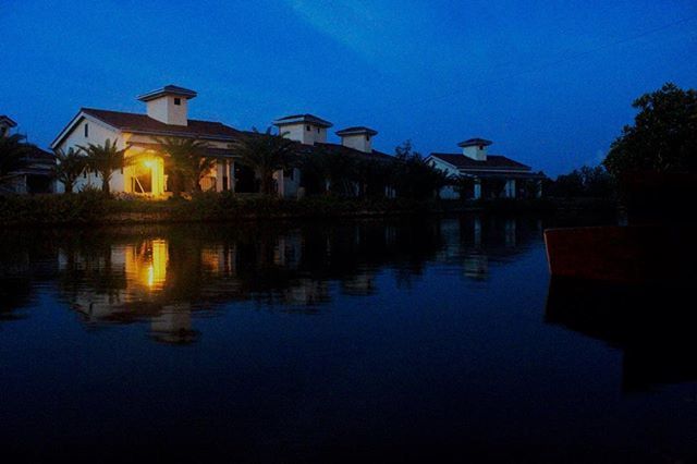 architecture, built structure, building exterior, reflection, water, clear sky, blue, waterfront, illuminated, house, bird, silhouette, dusk, sky, outdoors, river, lake, tree, sunset, copy space