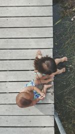 High angle view of siblings sitting on pier over lake