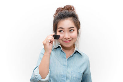 Portrait of young woman using smart phone against white background