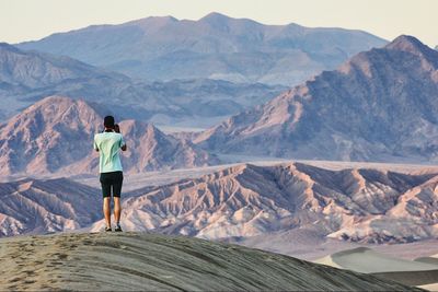 Rear view of man standing on mountain against sky