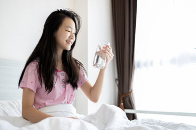 Beautiful woman drinking glass on bed