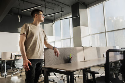 Rear view of young man using mobile phone while standing in cafe