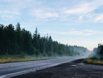 Road by trees against sky