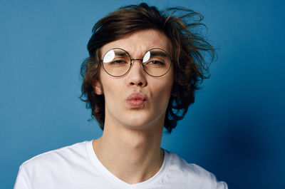 Portrait of mature man wearing eyeglasses against blue background