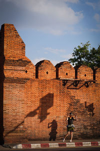 Full length of people on brick wall against sky