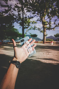 Cropped image of man holding hand against blurred background