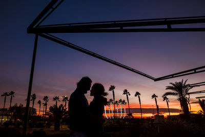 Silhouette couple romancing in park at sunset