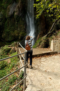 Rear view full length of woman standing by waterfall