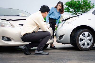 People standing by car on road