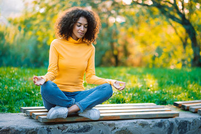 Young woman smiling while sitting on yellow during autumn