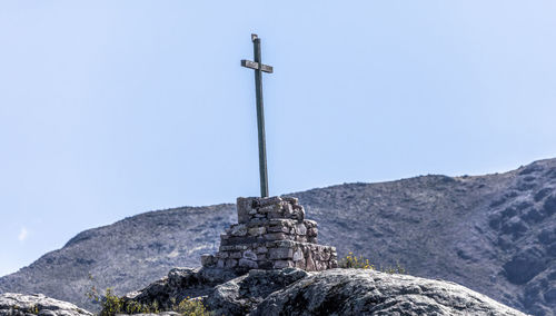 Low angle view of cross on rock against sky