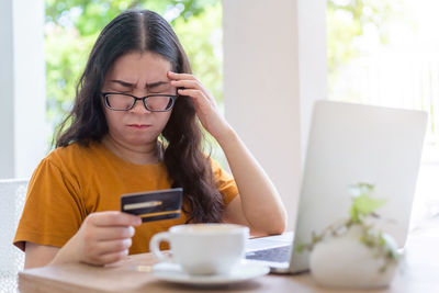 Young woman using mobile phone while sitting on table
