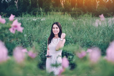 Portrait of smiling woman standing by flowering plants