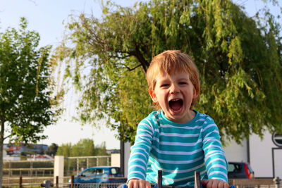 A blond boy with a wide open mouth on a blurred green background. emotional five-year-old boy  