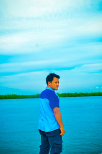 Boy standing in lake against sky