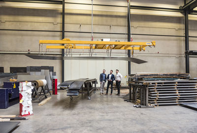 Three men standing on factory shop floor