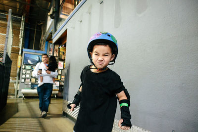 A young boy wearing a helmet makes a silly face for the camera