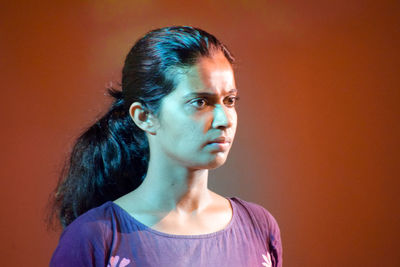 Portrait of young woman looking away against gray background