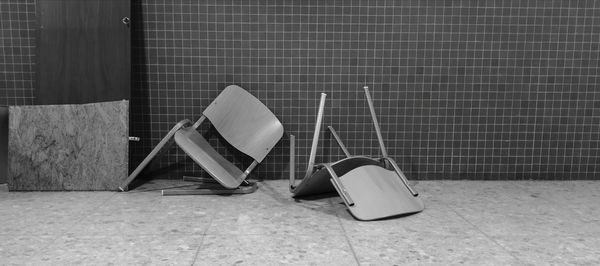 Empty chairs on tiled floor against wall