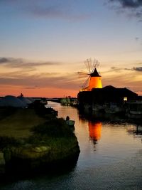 Silhouette built structure by sea against sky during sunset