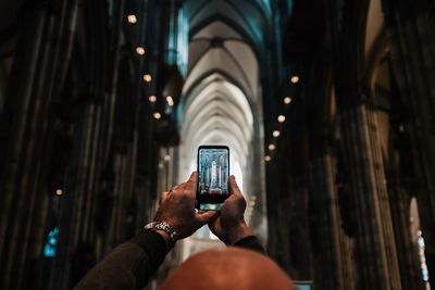 Cropped image of man photographing church with mobile phone
