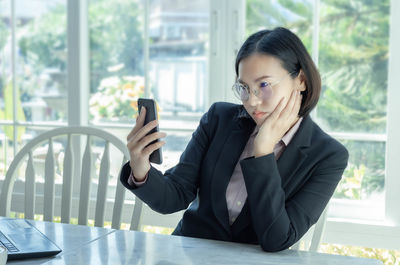 Businesswoman talking on phone while sitting on table