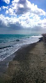 Scenic view of beach against cloudy sky