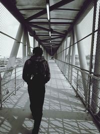 Rear view of man walking on bridge