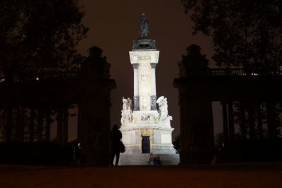 Statue in illuminated city against sky at night