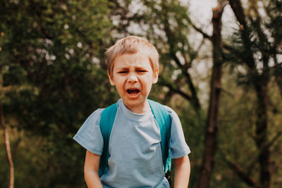 Boy looking at camera against trees