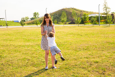 Full length of woman with arms raised on field