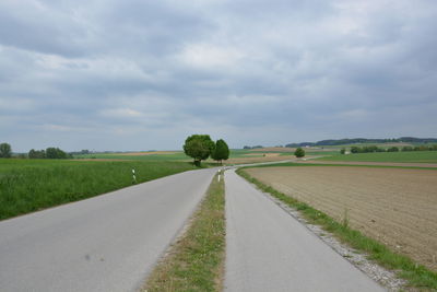 Road amidst field against sky