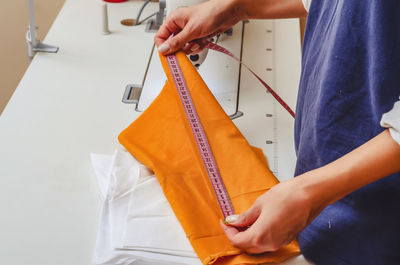 Dressmaker measures the cloth for sewing clothes with measuring tape