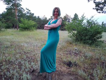 Portrait of woman standing on field against trees