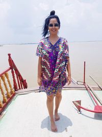 Portrait of smiling woman standing on boat deck against sky