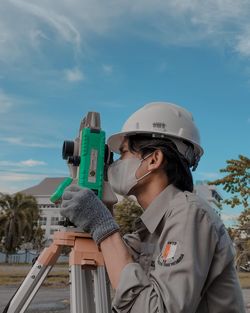 Man holding camera against sky